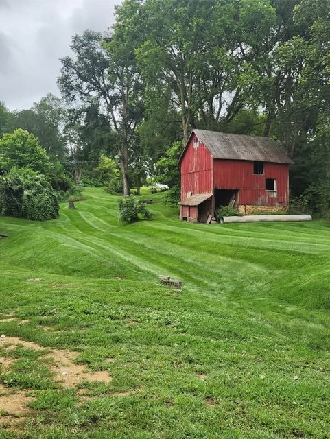 Freshly mowed large lawn near a red barn